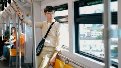 Young Man in a Beige Shirt and Pants Traveling by City Train