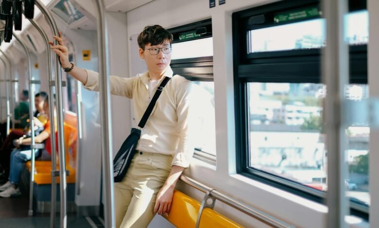 Young Man in a Beige Shirt and Pants Traveling by City Train