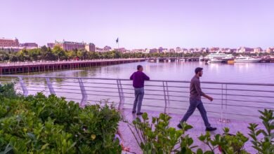 a couple of men walking across a bridge over a river