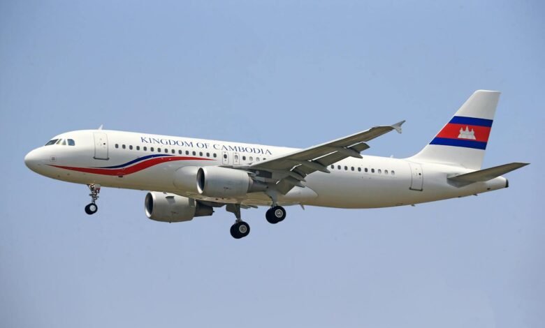 A commercial airplane flying in clear sky with Cambodia's national insignia.