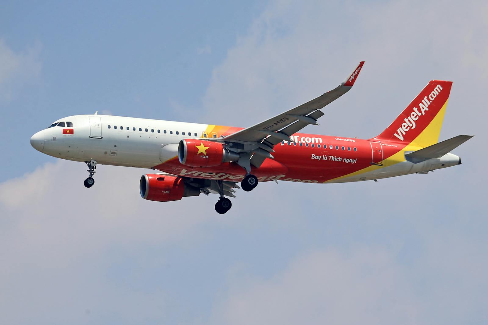 A VietJet Air Airbus A320 captured mid-flight against a clear sky, showcasing vibrant branding.