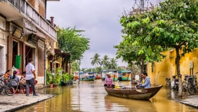 two women riding boat beside brown house