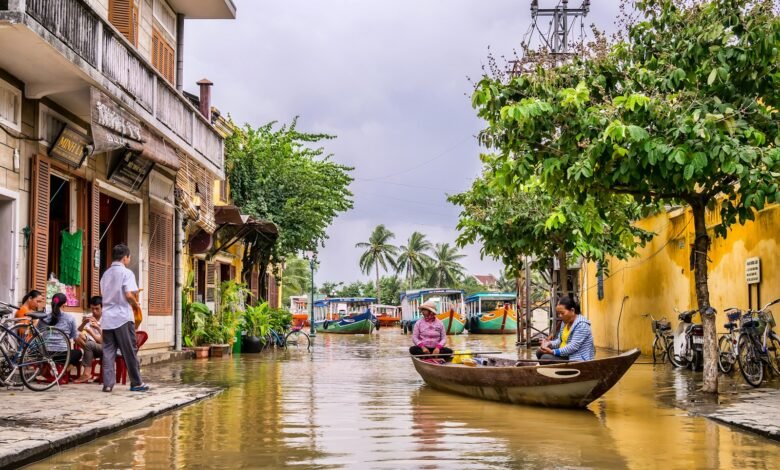 two women riding boat beside brown house