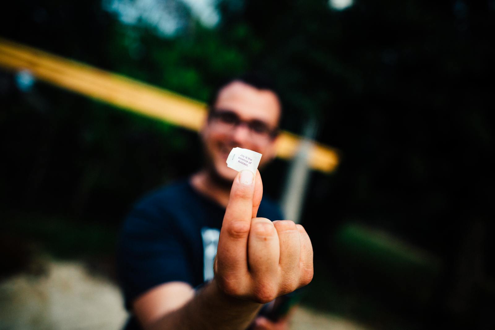 Selective Focus Photo of Man in Black T-shirt Hand Glasses Holding Out Piece of Paper