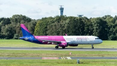 Wizz Air Airbus A321 taxiing at Hamburg Airport with control tower in view, outdoors.