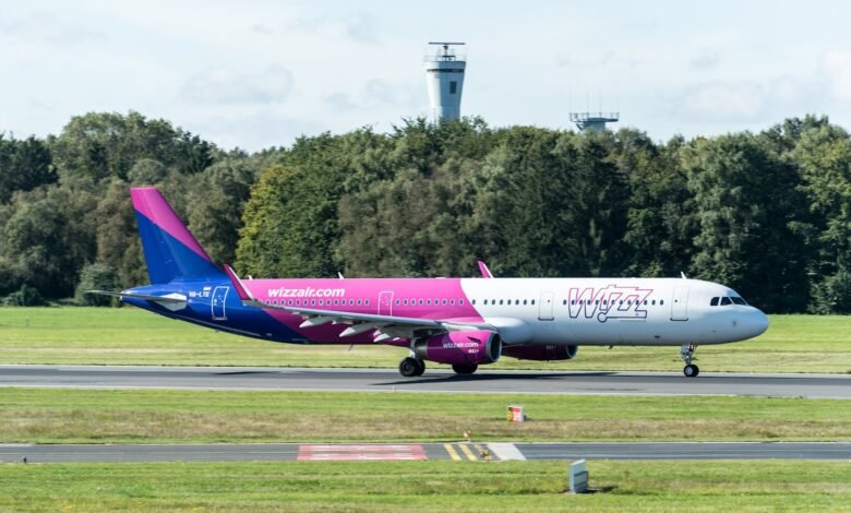 Wizz Air Airbus A321 taxiing at Hamburg Airport with control tower in view, outdoors.