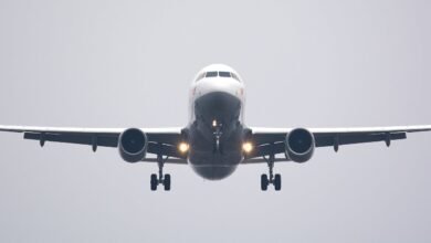 A commercial airliner captured head-on, preparing to land against a cloudy sky.