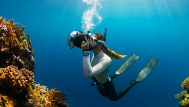 a woman scubas in the ocean with a camera