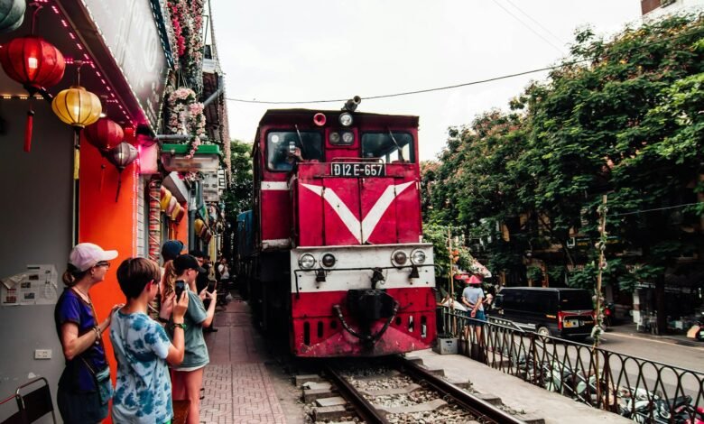 A red train traveling down train tracks next to a crowd of people