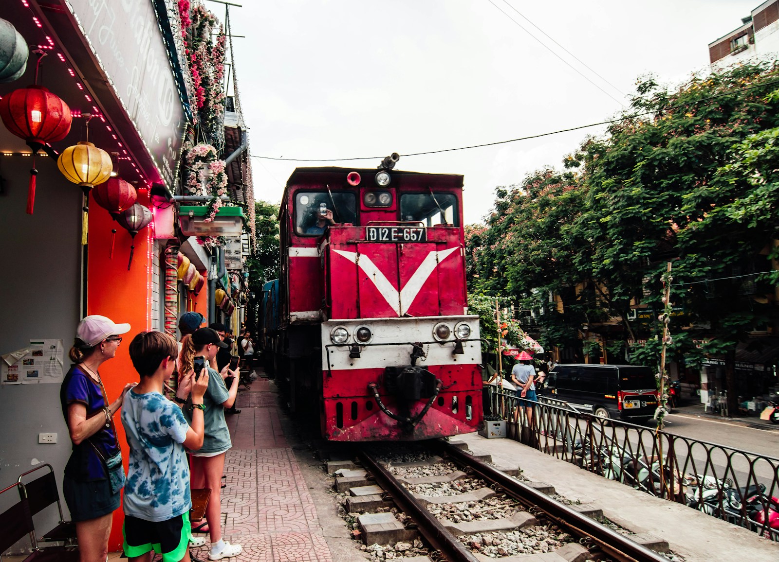 A red train traveling down train tracks next to a crowd of people