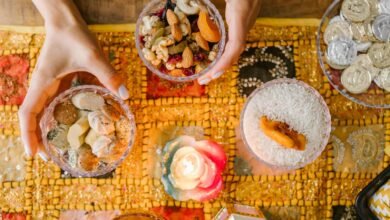 Hands arranging traditional Persian snacks for Nowruz on a decorated table with candlelight.