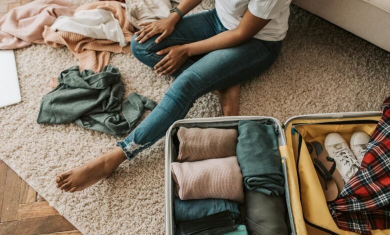 Woman organizing clothes while sitting on floor with open suitcase, preparing for a trip.