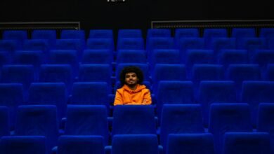 a man sitting in a blue chair in a theater