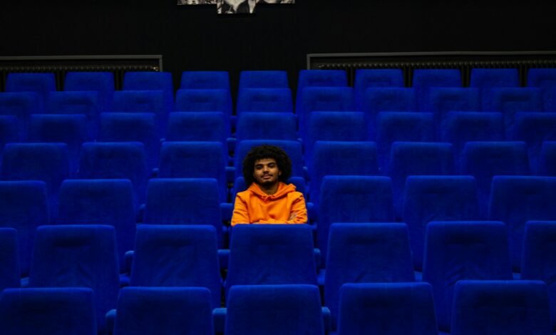 a man sitting in a blue chair in a theater