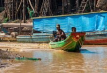 man in black shirt riding on green and yellow boat during daytime