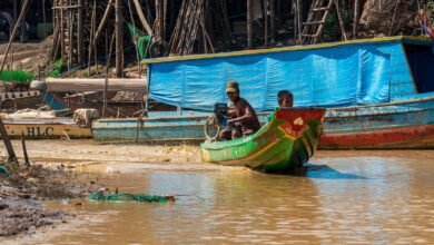 man in black shirt riding on green and yellow boat during daytime