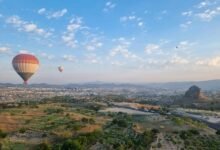 two hot air balloons flying over a city