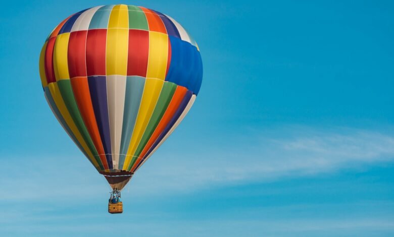 panning photography of flying blue, yellow, and red hot air balloon