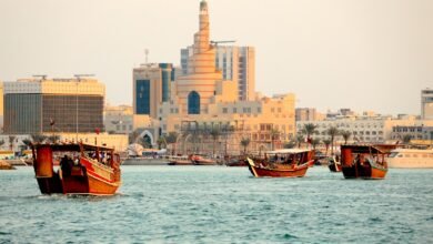 a group of boats in a body of water with buildings in the background