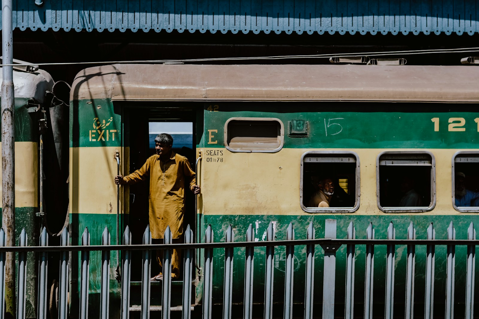 woman in brown coat standing beside green train