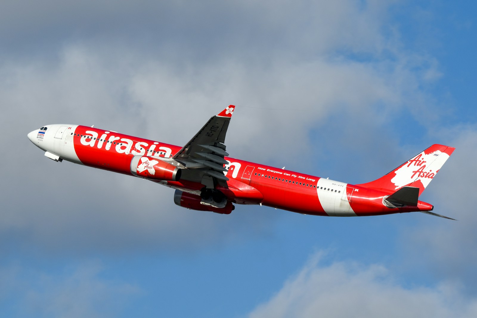 A large air plane flying through a cloudy sky
