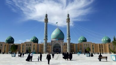 people walking on street near mosque under blue sky during daytime