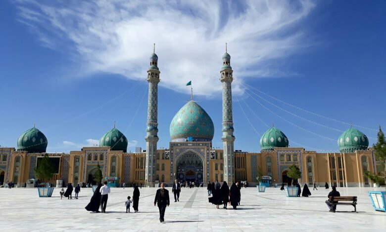 people walking on street near mosque under blue sky during daytime