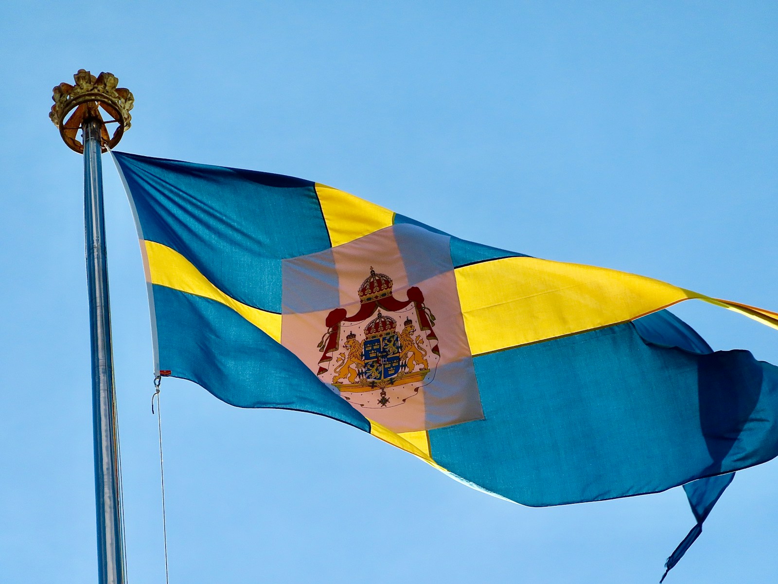 a flag flying in the wind with a blue sky in the background