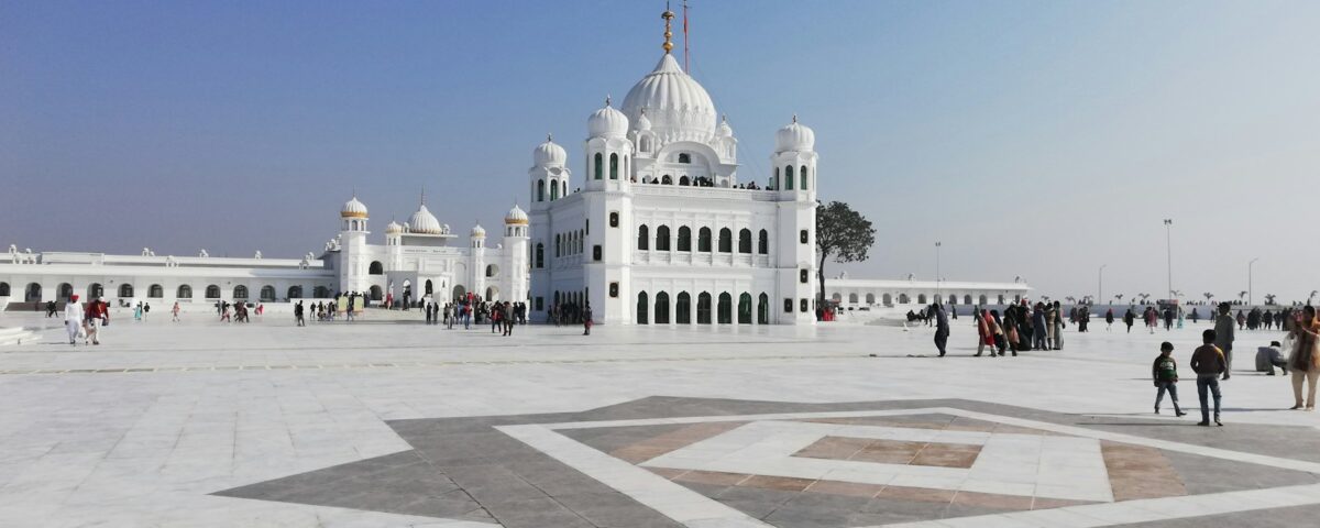 people walking on street near white concrete building under blue sky during daytime