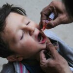 a little boy getting his teeth brushed by an adult